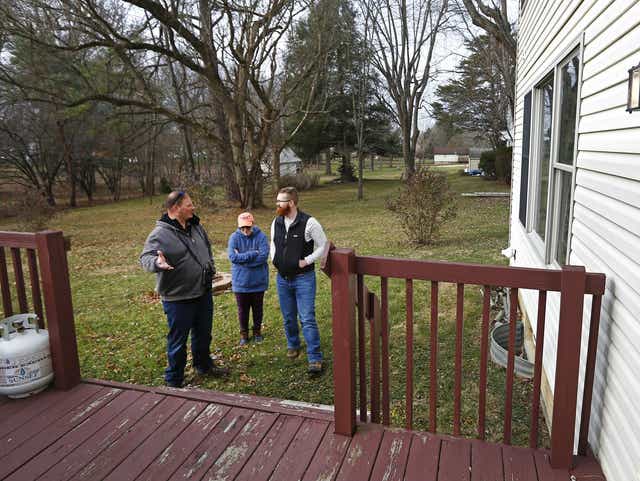 ghows-OH-c8e5aa45-eed3-451e-8cb8-27ea1e3e9733-9185620d Three people standing on a porch looking at something.